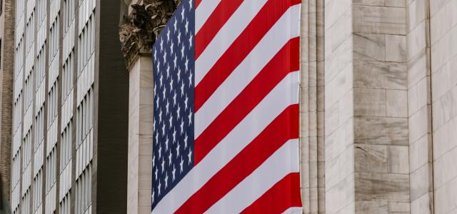 a large american flag hanging from the side of a building by Hans Isaacson courtesy of Unsplash.